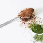 Een lepel colostrum poeder op een houten tafel met een achtergrond van producten voor gezondheid en welzijn.