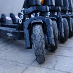 Een persoon die een scootmobiel bestelt, met verschillende modellen op de achtergrond, waaronder opvouwbare en driewielscooters.